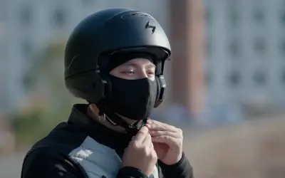 Motocyklista zapina czarną kominiarkę pod kaskiem.